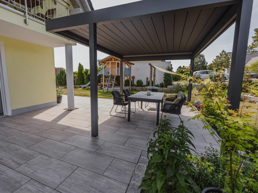 überdachte Terrasse mit Sitzecke mit Terrassenplatten Calido Grano Grau