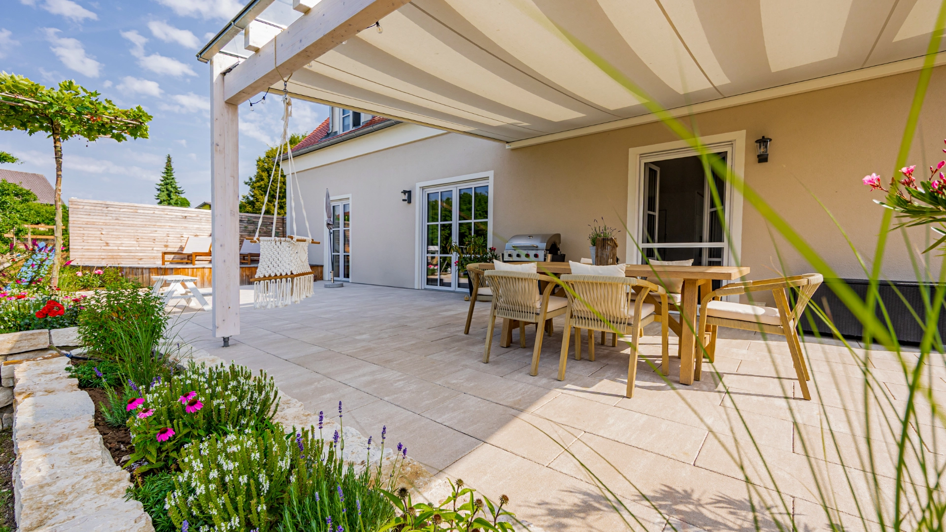 überdachte Terrasse mit Tisch und Stühlen mit Lamina-Platten in der Farbe Jura verlegt